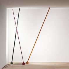 two different colored sticks sticking out of a white wall next to each other in an empty room