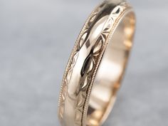 a wedding ring with an intricate design on the inside and outside, sitting on top of a gray surface