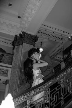 a bride and groom kissing on the stairs at their wedding reception in black and white