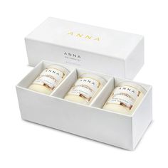 three white candles in a box on a white surface with the words ama printed on it