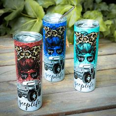 three different colored tumblers sitting next to each other on a wooden table with plants in the background