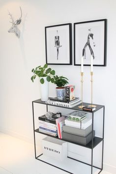 a black and white shelf with two pictures on it next to a potted plant