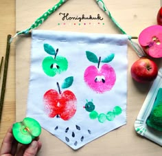 an apple painting is being displayed on a table with apples and other crafting supplies