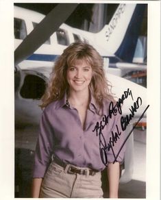 an autographed photo of a woman standing in front of a jet airliner