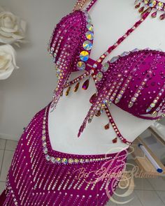 a belly dancer's bra and skirt are on display in a room with white roses