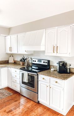 a kitchen with white cabinets and stainless steel stove top oven, dishwasher and coffee maker