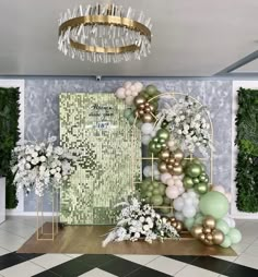 a room filled with lots of balloons and greenery next to a chandelier