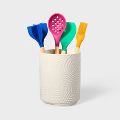 four colorful toothbrushes in a white cup