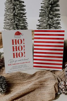 two christmas cards sitting next to each other on top of a wooden table covered in pine cones