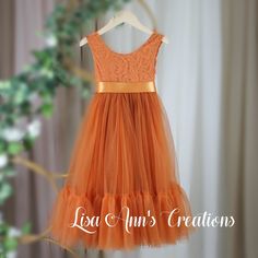 an orange tulle dress hanging on a hanger in front of a window with the words loa ann's creations