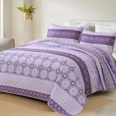 a bed covered in purple and white bedspread