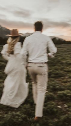 a man and woman are walking through the grass