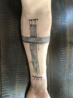 a person with a cross tattoo on their foot and the word jesus written in hebrew