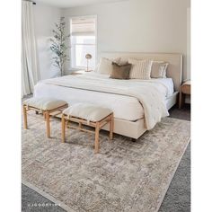 a large white bed sitting in a bedroom on top of a rug