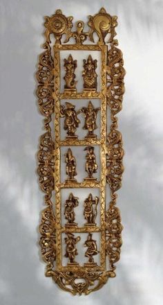 an ornately decorated gold wall hanging with figures on it's sides and in the middle