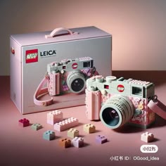 a camera and some legos on a pink surface with the box open to show it's contents