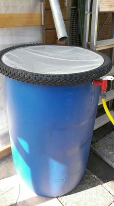 a large blue barrel sitting in the middle of a yard next to a building with a hose connected to it