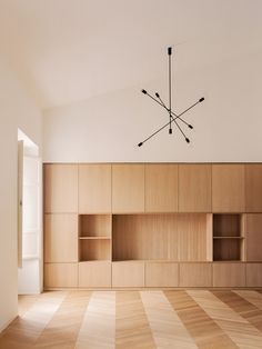 an empty room with wooden shelves and a chandelier hanging from the ceiling