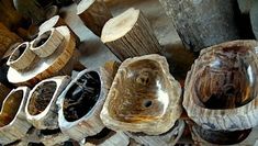 several wooden bowls and spoons are lined up on a table with wood slices around them