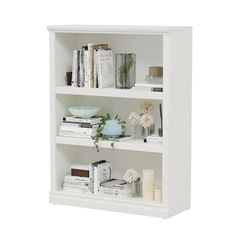 a white book shelf filled with books on top of a wooden table next to a vase