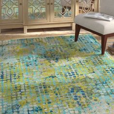 an area rug with blue, green and yellow colors in the middle of a living room