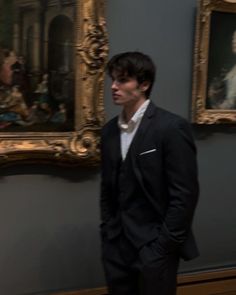 a man standing in front of some paintings