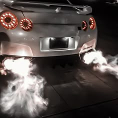 the front end of a white sports car with flames coming out of it