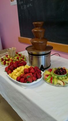 two plates of fruit on a table with a chocolate fountain