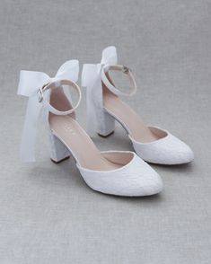 a pair of white shoes with bows on them