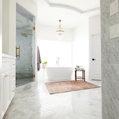 a bathroom with marble floors and white walls, along with a large bathtub in the center