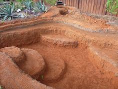 an open pit in the ground with plants growing out of it's holes and dirt