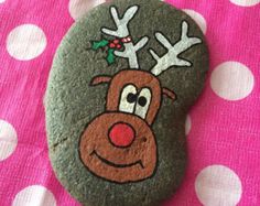 a rock with a reindeer painted on it sitting on top of a pink polka dot blanket