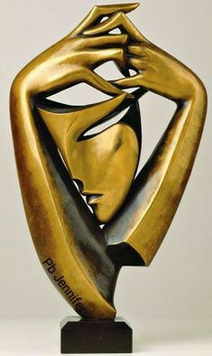 a gold sculpture with a woman's face and hands on her head, in front of a gray background