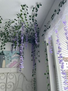 some purple flowers hanging from the ceiling in a room with white walls and blinds on it