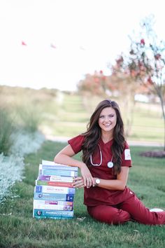 a woman sitting in the grass with some books