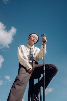 a man sitting on top of a chair holding a microphone in his right hand and wearing a tie