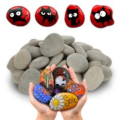 three hands holding rocks with faces painted on them and four other stones in the background