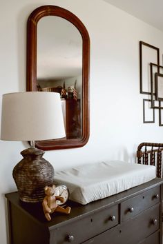 a bedroom with a dresser, mirror and lamp