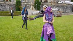 two people in costume are playing with a frisbee on the grass near a castle