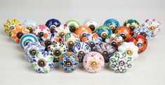 an assortment of colorful glass knobs on a white surface