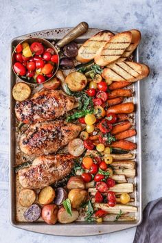 a tray filled with meat, vegetables and bread