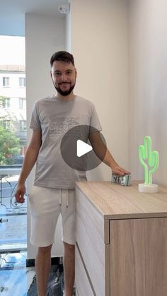 a man standing in front of a dresser with a cactus on it and a camera