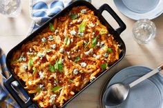 a casserole dish filled with pasta, cheese and parsley on a table