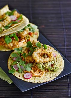 two tacos with shrimp, lettuce and sauce on them sitting on a blue plate