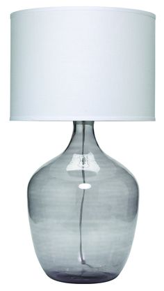 a gray glass lamp with a white shade on the base and a light bulb attached to it