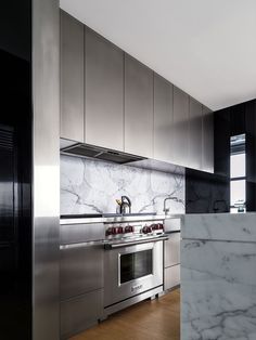 a kitchen with marble counter tops and stainless steel appliances, along with an oven in the center