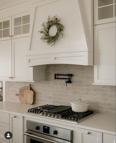 a stove top oven sitting inside of a kitchen next to white cabinets and counter tops