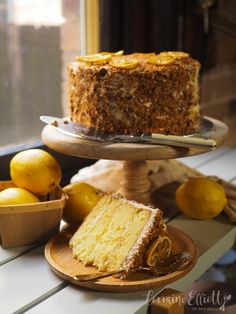 a piece of cake sitting on top of a wooden plate next to lemons and a bowl