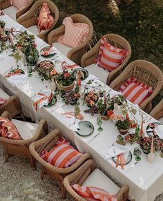 an outdoor table set up with place settings and orange striped napkins on the table