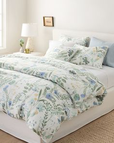 a white bed with blue and yellow flowers on it